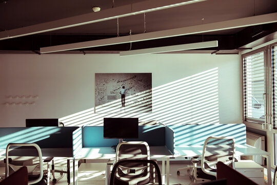 Empty modern open-plan office with sunlit workstations