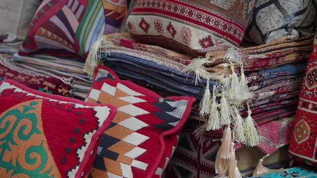 Close-up shot of stacked traditional textile cushions with tassels in warm colors.