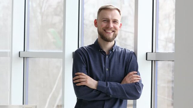 Smiling man with crossed arms looking at window indoors