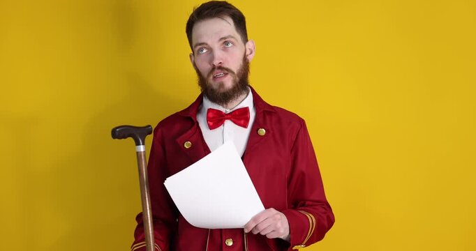 Professional actor in suit with walking cane and script performing on yellow background. Camera moving up