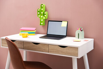Naklejka premium Stylish workplace with laptop, lamp, cup of tea and stationery indoors