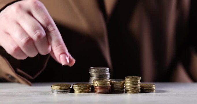 Woman stacking coins at wooden table, closeup