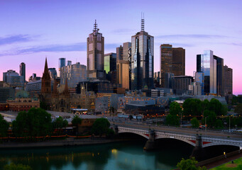 Naklejka premium Melbourne city sunset and moonrise skyline with views of St Paul’s Cathedral, skyscrapers, and the Yarra River in Victoria, Australia