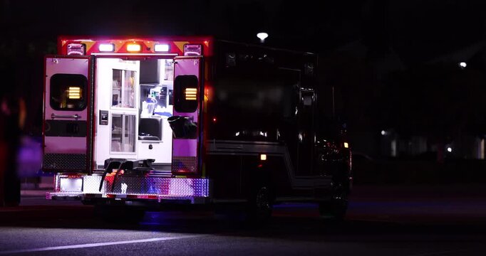 An ambulance responds to an emergency at night with open back doors.