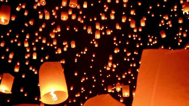 Many lanterns flying in night sky.