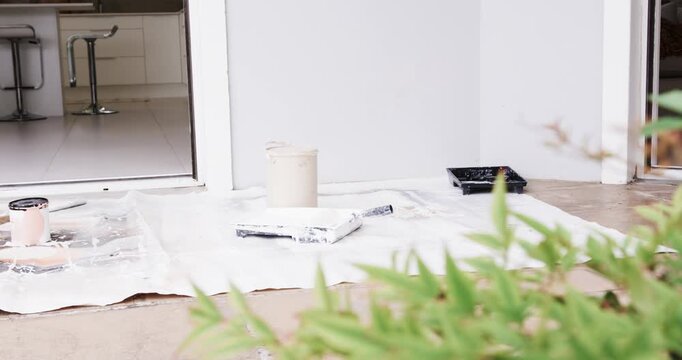 Camera is shifting while painting supplies are sitting on drop cloth at doorway, preparing to paint