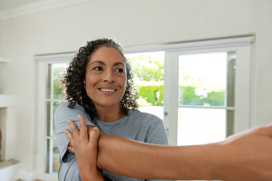 Adult African American woman holding other person's forearm near sliding glass doors in bright home