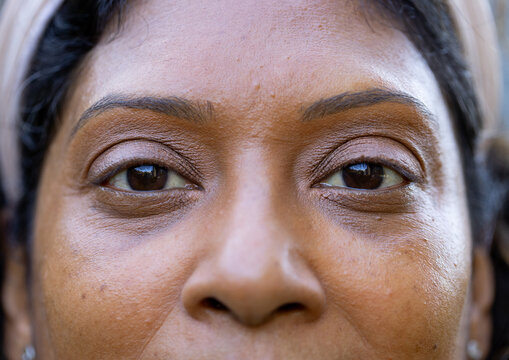 Close-up woman tapping phone and launching skincare overlay highlighting pores, lines, eye makeup