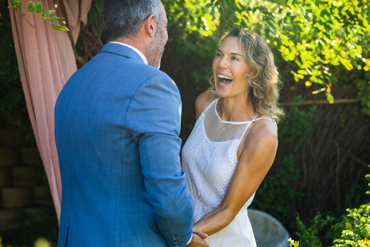 Man holding woman in white dress, squeezing and causing animated hearts floating for wedding