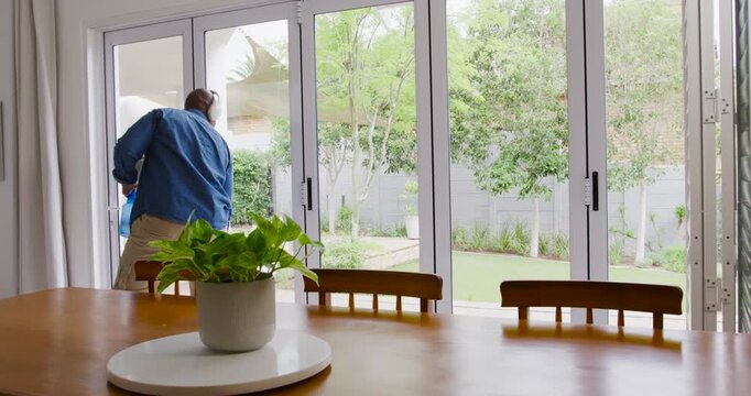 Man noticing open door, cleaning glass doors with spray bottle and squeegee at home, copy space