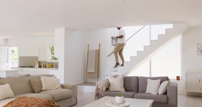 Man holding laundry basket coming down stairs after laundry pickup into bright living room