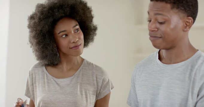 African American couple at kitchen counter he talking urging she checking item with tool smartwatch