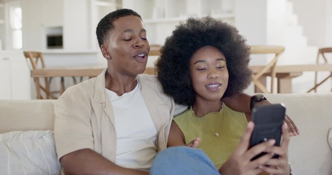 African American couple on couch at home, phone clip sparking man miming, woman pausing, cuddling