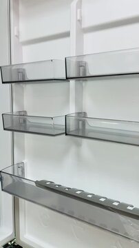 Empty refrigerator door shelves transparent bins, clean white interior with three clear plastic door bins and reinforced lower.