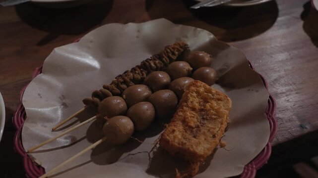Traditional Indonesian meal featuring Soto Boyolali soup served with rice, quail egg satay, chicken intestine satay, and local street food snacks. Authentic culinary dining