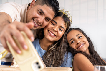 Obraz premium Hispanic family celebrating birthday taking a selfie indoors