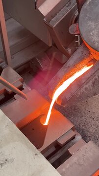 worker hot melted metal pouring into the sand mold in manufacturing die casting process