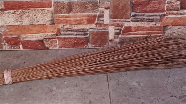 Traditional Coconut Leaf Stick Broom Lying on Stone Floor Surface