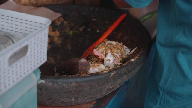 Traditional Indonesian lotek being prepared and served at a street food stall in Bandung, Indonesia. Fresh vegetables mixed with peanut sauce and enjoyed as a local culinary experience in an authentic