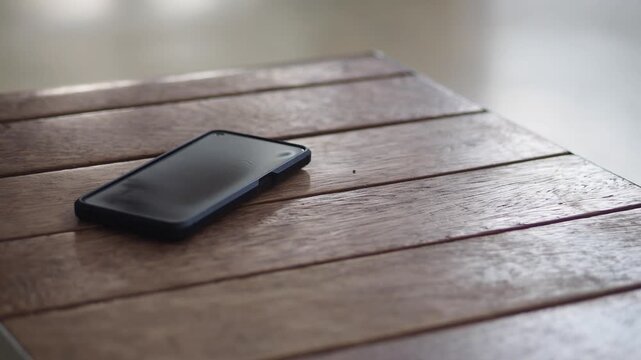 Smartphone rests on a wooden table surface showcasing its modern design and sleek black finish.