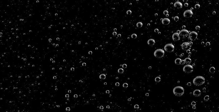
Abstract water bubbles floating on dark black background, minimal liquid texture with tiny air droplets in macro detail. Elegant splash effect for backdrop, overlay, science or beverage concept. 