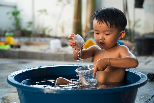 Toddler Playing with Water in Plastic Tub Outdoors