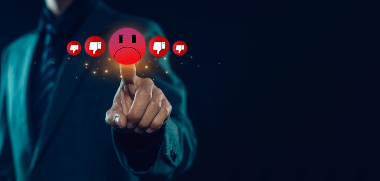 Businessman hand pressing negative feedback icon with red sad face and dislike symbols, customer experience rating, bad review concept, service quality issue, digital interface, complaint.