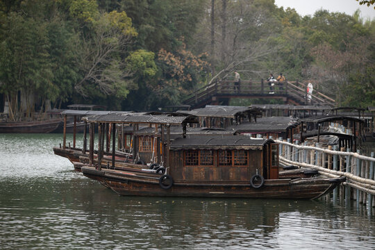 Traditional black-sailed boats glide gently along the scenic canals of Wuzhen Water Town, surrounded by ancient architecture and timeless charm