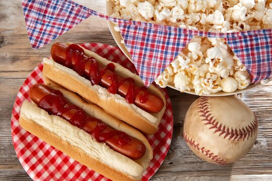 Classic picnic spread with hot dogs, popcorn, and baseball