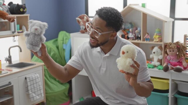 Man holding a plush chick and a gray cat puppet with hands in a children's playroom; playful bonding.