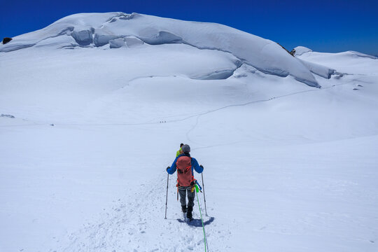 Mountaineers in rope team with crampons descending, mountain summit Parrotspitze on Monte Rosa massif and glacier panorama in Pennine Alps, Switzerland