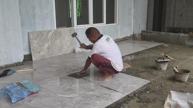 A worker cleans and smooths wet cement before installing granite tiles on top