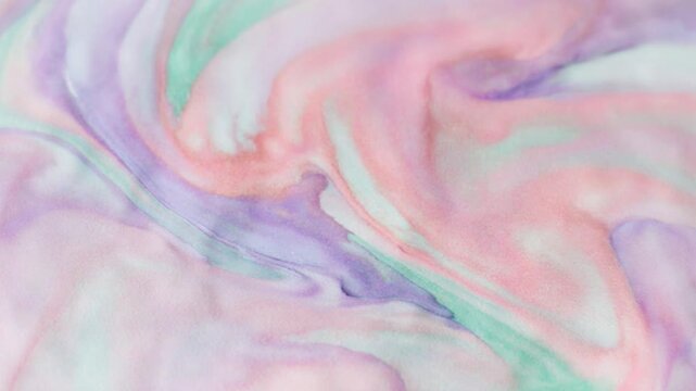 Close-up of a serene pastel watercolor abstract background with soft flowing shapes in lavender, pink, and mint green, featuring fluid paint bleeds on a textured paper surface.