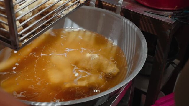 Traditional Indonesian batagor being fried, prepared, served with peanut sauce, and eaten at a local street food stall in Bandung. Authentic culinary scene showcasing popular West Java snack culture