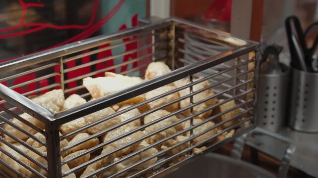 Traditional Indonesian batagor being fried, prepared, served with peanut sauce, and eaten at a local street food stall in Bandung. Authentic culinary scene showcasing popular West Java snack culture