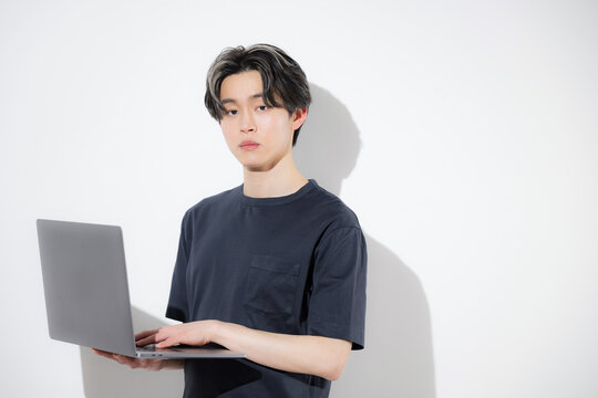 ノートパソコンで作業する若いフリーランスエンジニアやデザイナーなどの白背景カメラ目線　自然言語のプログラミングで効率化や時短でaiを使うイメージ