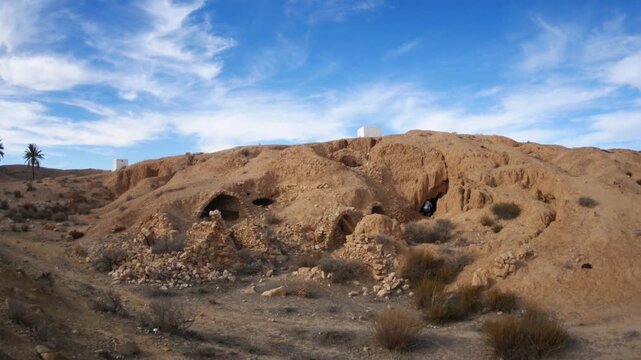 Panorama: Traditional troglodyte houses carved into rock in Matmata, Tunisia. Ancient underground dwellings in arid desert landscape, historic Berber architecture and cultural heritage site