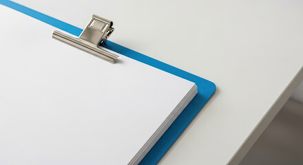 Obraz premium Blank clipboard on white desk with blue clip for organization 
