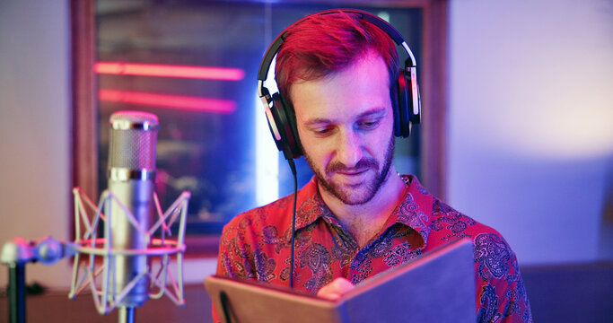 Writer, notebook and man in recording studio, music production or song composition with neon light. Notes, headphones and songwriter writing lyrics for album idea, sound or creative musician with mic