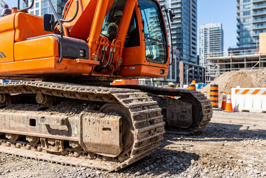 Close up of an orange excavator track on a city construction site in summer