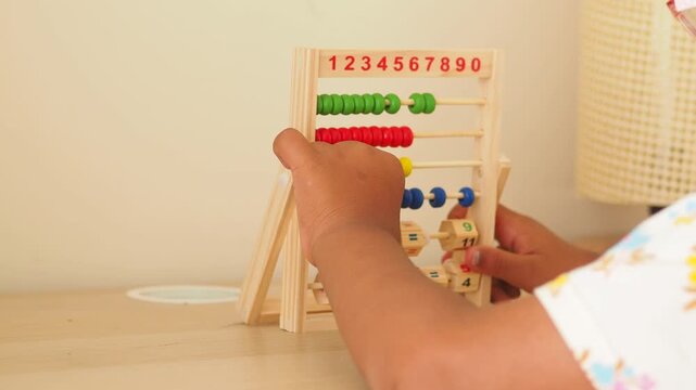 Child learning to count on a wooden abacus, engaging in educational play activity.