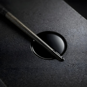 Close-up of traditional Japanese Suzuri inkstone with fresh black ink and a Sumi ink stick, Zen minimalist style