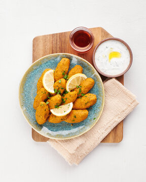 Turkish lentil kofte, mercimek koftesi, served with yogurt sauce, lemon slices and tea on wooden board, top view.