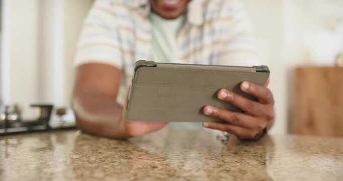 Adult male holding tablet in folio cover at kitchen counter, tapping and swiping to browse