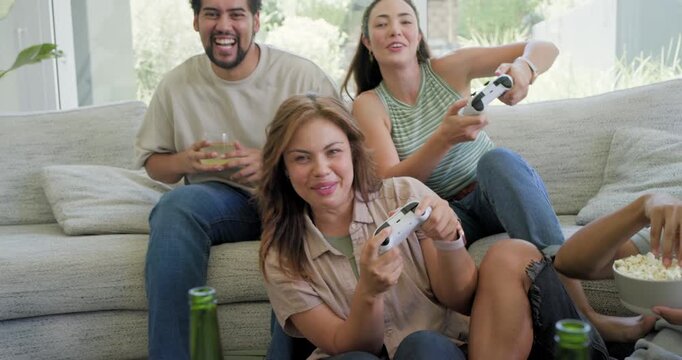 Diverse friends reacting to game cue, holding white controllers and passing popcorn at home for fun