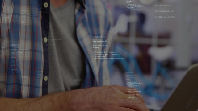 Typing man wearing plaid shirt and gray tee editing code on silver laptop at coworking space