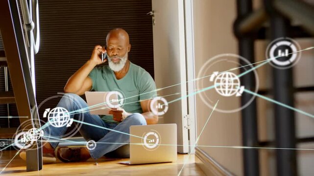 Holding phone, paper, man wearing teal tee sitting in doorway hardwood-floor, laptop network moving