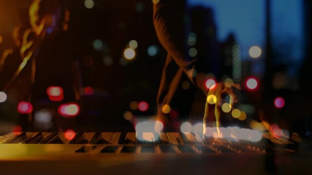 Musician hands hovering then pressing keys and tweaking synth with city bokeh overlay for recording
