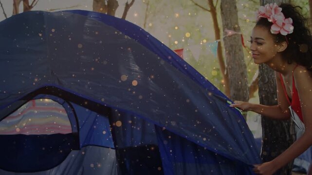 Woman approaching tent, pulling flysheet to secure dome for camping, particles highlighting zipper