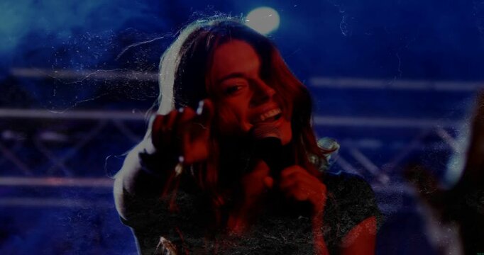 Singer lifting arm, bringing mic close, showing smile, pointing, engaging crowd reaching upward